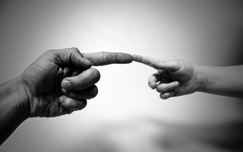 Two people reaching with one finger towards each other, connecting. Signifies a contact between two people.