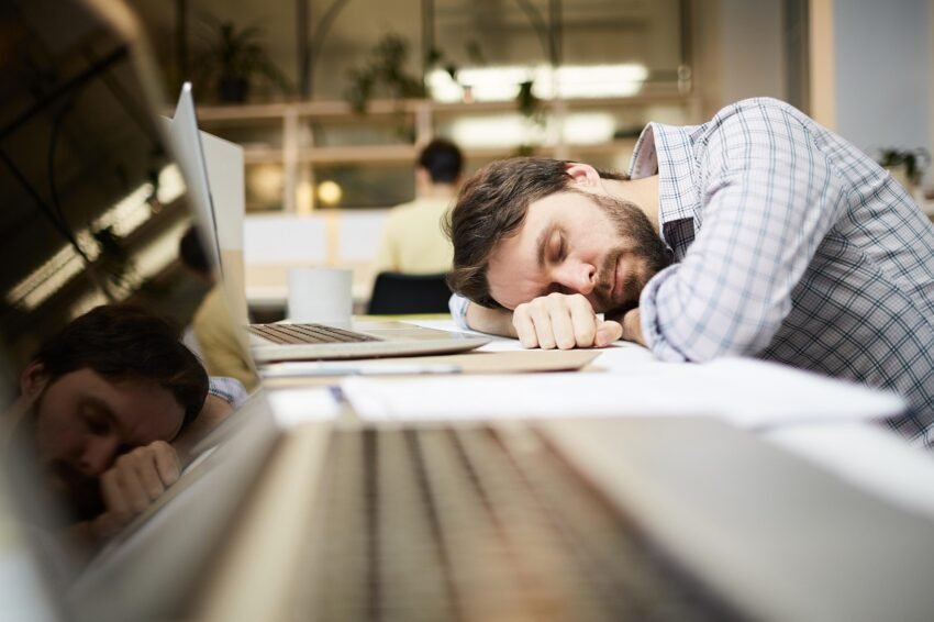 Man resting his head on his hands, laying on the working table, and his eyes closed. Regenerating energy levels.