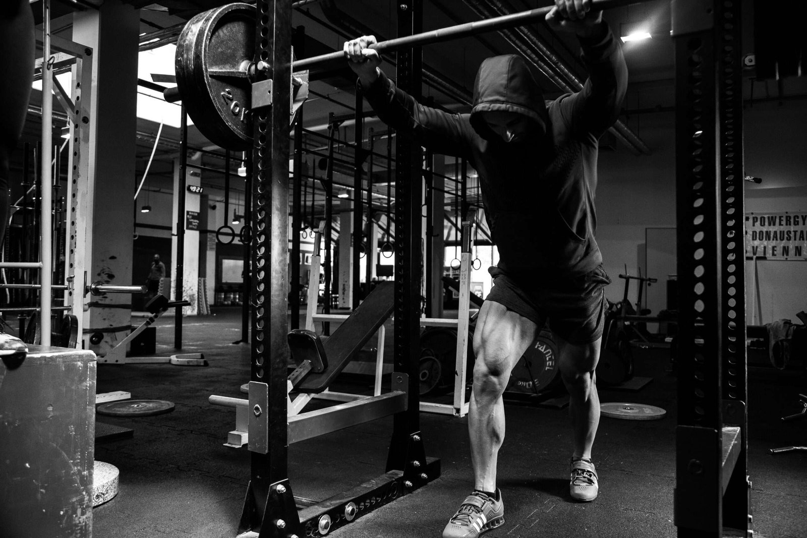 An athlete standing behind the squat rack in a fitness gym.